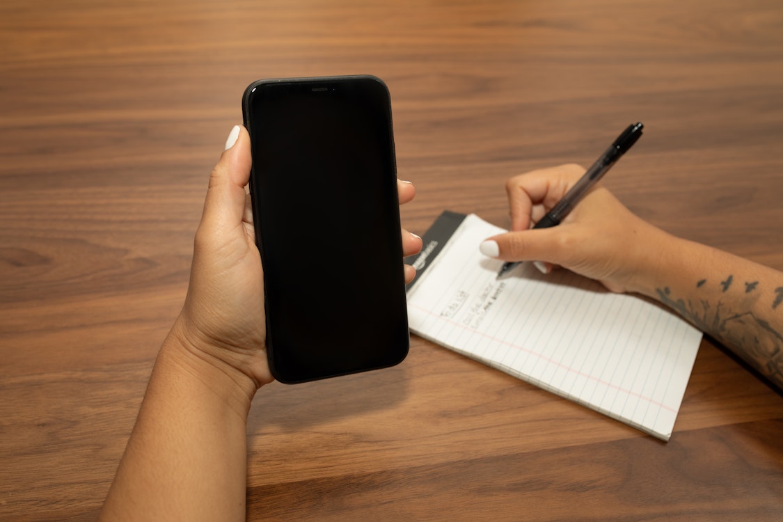 Hand holding phone while writing